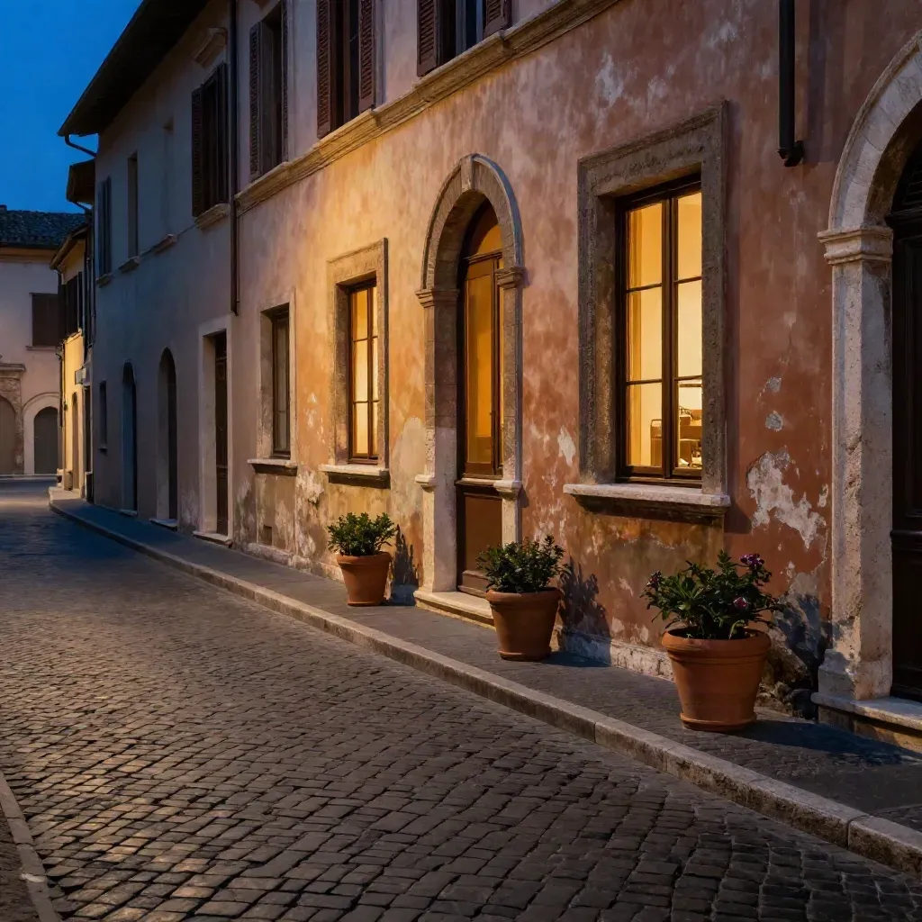 Strada romana serale con basoli, facciata in travertino, arco e finestre calde nella foschia blu.